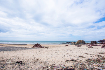 Beautiful sandy beach with rocks and bright cloudy sky above turquoise sea.Scenic landscape of Pembrokeshire coast, Uk.Paradise on Earth.Vibrant image with copy space.