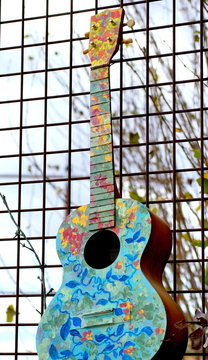 Acoustic colorful abstract guitar on a fence outdoors.