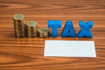TAX concept. TAX alphabet with stack of coin and business card or name card on wooden working table, business and financial concept.
