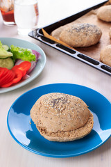 Naklejka premium Cooking healthy vegan burger with chickpea fritters, vegetables and whole-wheat bun with sesame and poppy seeds on white table for breakfast