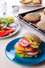 Healthy vegan burger with chickpea fritters, vegetables and whole-wheat bun with sesame and poppy seeds on white table for breakfast. Cooking, recipe