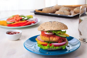 Healthy vegan burger with chickpea fritters, vegetables and whole-wheat bun with sesame and poppy seeds on white table for breakfast. Cooking, recipe