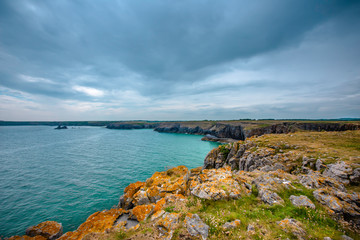 Fototapeta na wymiar Dramatic rocky coastline of Pembrokeshire,United Kingdom on cloudy summer day.Scenic landscape without people.
