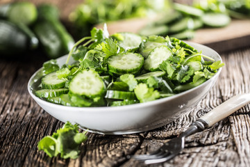 Sliced cucumber on a plate with parsley herb on rustic oak wood.