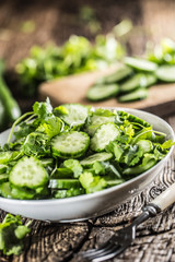 Obraz premium Sliced cucumber on a plate with parsley herb on rustic oak wood.