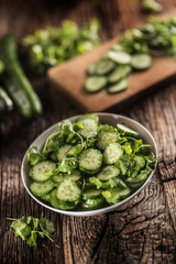 Sliced cucumber on a plate with parsley herb on rustic oak wood.