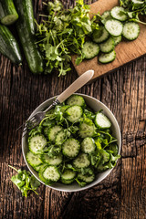 Sliced cucumber on a plate with parsley herb on rustic oak wood.