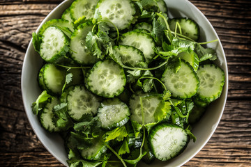Obraz premium Sliced cucumber on a plate with parsley herb on rustic oak wood.