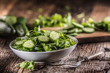 Sliced cucumber on a plate with parsley herb on rustic oak wood.