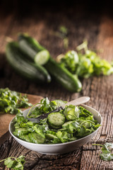 Sliced cucumber on a plate with parsley herb on rustic oak wood.