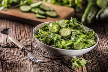 Sliced cucumber on a plate with parsley herb on rustic oak wood.