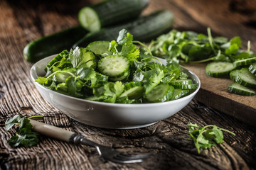 Sliced cucumber on a plate with parsley herb on rustic oak wood.