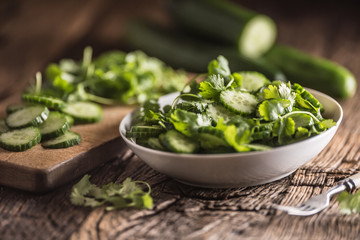 Sliced cucumber on a plate with parsley herb on rustic oak wood.