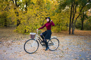 Fototapeta premium young woman riding on retro bicycle in the autumn park 
