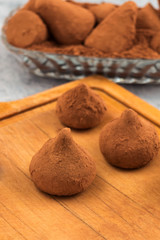 Chocolate candies with cocoa powder on wooden background.