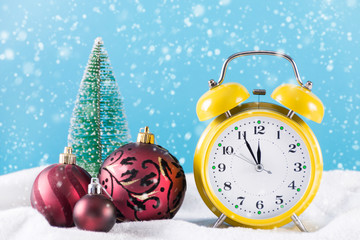Christmas ball decoration and retro clock on snow and blue background. Winter day and snowflakes falling down. New Year and Christmas time concept