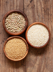 Organic lentils, couscous and sesame seeds in wooden bowls.