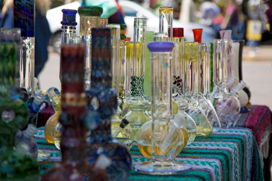 Close Up, Isolated View of Glass Bongs on Flea Market Table, Sunlit Out of Focus Background