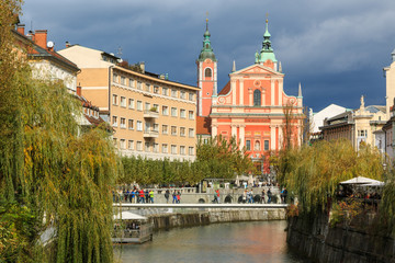 View of Ljubljanica river in old city with dark stormy clouds in the background on an autumn day, Ljubljana, Slovenia