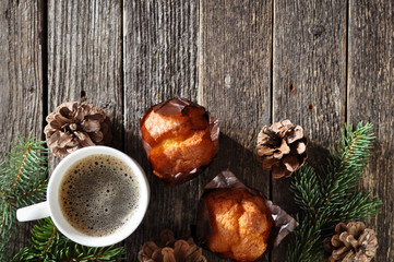 Christmas Breakfast of two cupcakes and a Cup of hot coffee on a wooden table with fir