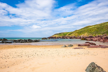 Fototapeta na wymiar Scenic landscape of Pembrokeshire coast, Uk.Sandy beach with few rocks, turquoise sea and blue sky with few clouds.Paradise location Uk.