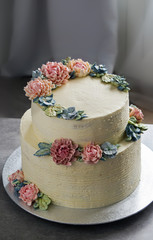 Obraz na płótnie Canvas big wedding cake, decorated with buttercream flowers, on the grey stone background