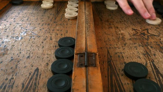 Two young men playing backgammon on a wooden table with dices