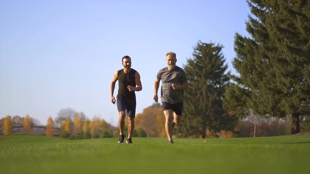 The two happy men running on the grass. slow motion