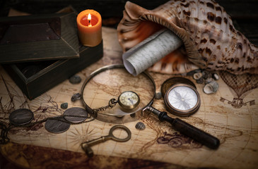 Fototapeta na wymiar Old brass compass lying on old map with treasure chest and coins