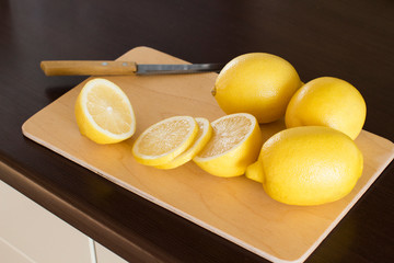 sliced lemons on a wooden cutting board on a dark wooden kitchen table
