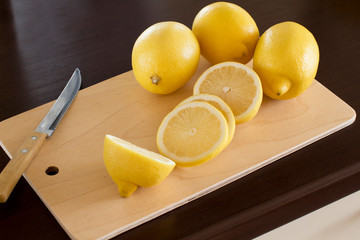sliced lemons on a wooden cutting board on a dark wooden kitchen table