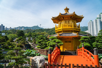 Fototapeta premium Beautiful golden pagoda in a peaceful garden surrounded by trees with a blue sky in the city