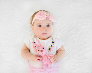 sad baby girl 4 months old holding her toy starring in camera