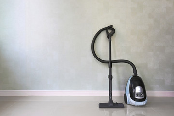 Vacuum cleaner on white concrete background in the house.