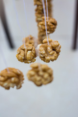 Walnuts halves on long thread - preparation blank for making churchkhela sweet dessert homemade candy - traditional Georgian food with grape juice, nuts and corn or white flour.