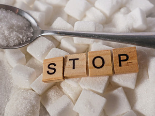 h pile of white sugar cubes and stop word in block letters as advise on addiction calories excess...