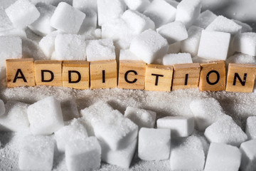 pile of sugar cubes and addiction word in block letters as advise on calories excess and sweet...