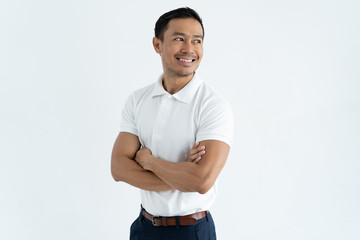 Happy confident Asian male entrepreneur crossing arms on chest and looking away. Positive successful young employee standing against white background. Aspirations concept
