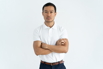 Serious Asian businessman in white tshirt looking at camera. Successful young programmer with...