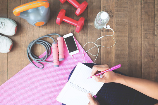 Top view of sporty woman writing on notebook, planning workout