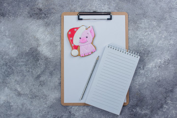 Christmas Ginger Cookie Cute Pig Symbol Year and empty paper notebook on a gray stone concrete table background. Top view with copy space, flat lay