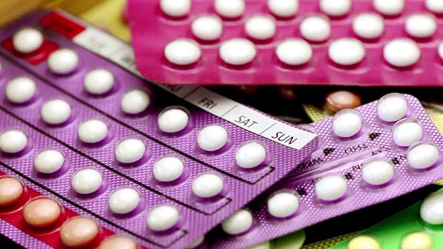 Oral contraceptive pill on pharmacy counter with colorful pills strips background.