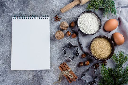 Christmas Recipe Menu Concept. Ingredients for cooking christmas baking and empty white paper notebook on gray stone background. Top view with copy space.