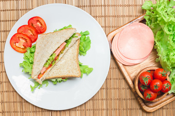 Top view of sanwiches with ham and tomatoes vegetable on dish,and wooden board