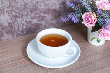 Fototapeta na wymiar A cup of Chinese tea on wooden table. Beverage for healthy with rose flower in pot