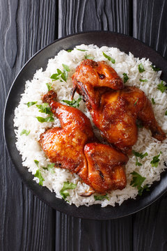 Indonesian main course baked chicken in garlic, soy, ginger and honey sauce served with rice on a plate close-up. Vertical top view