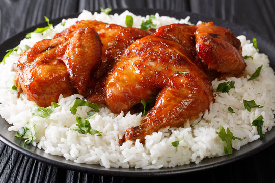 Traditional Indonesian chicken baked in a sauce of garlic, soy, ginger, and honey, served with rice on a plate close-up. horizontal