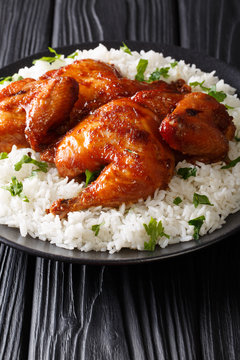 Spicy half chicken baked with lots of garlic, soy sauce, ginger and honey, served with rice on a plate close-up. Vertical