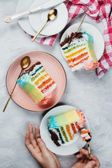 Flat lay of rainbow vegan cake pieces on grey background