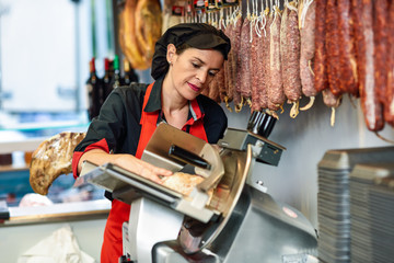 Female butcher cutting york ham in a cutting machine